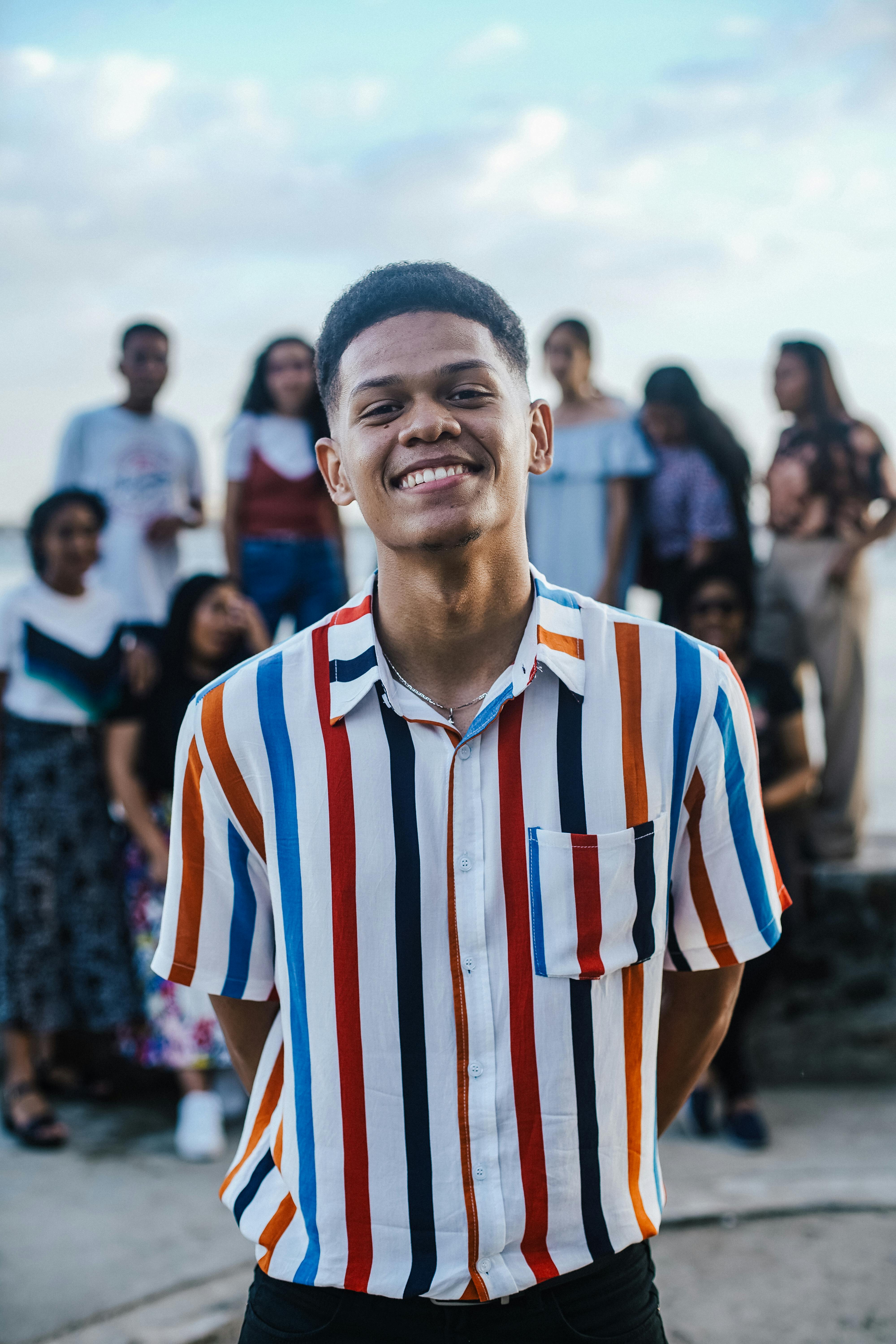 Young man smiling with community gathered behind him